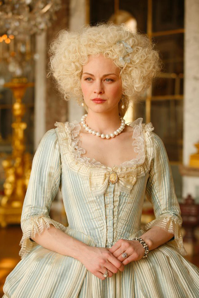 Raphaelle Agogue as Marie Antoinette wearing a blue and white striped gown in the episode "Countdown to the Revolution" of the 2011 mini-series "Versailles."