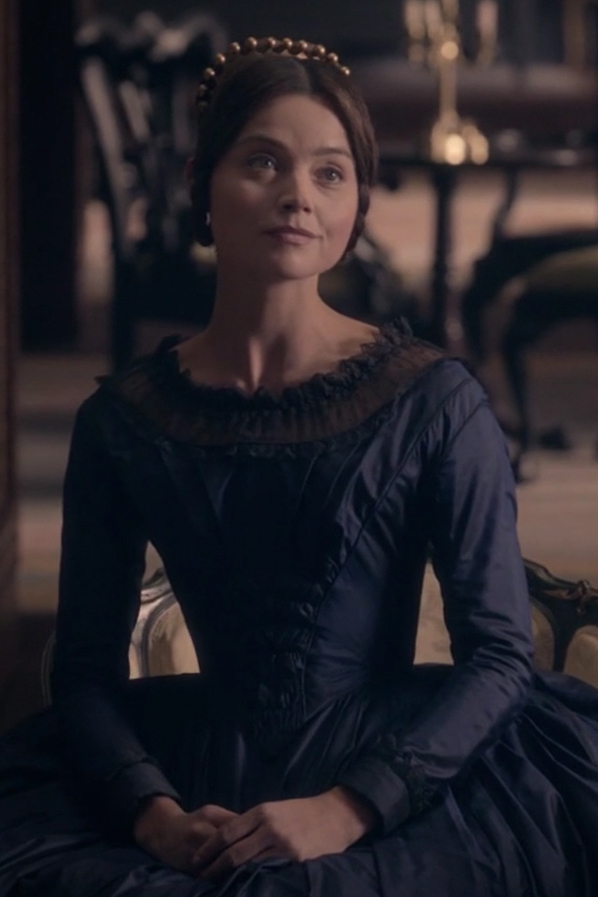Jenna Coleman as Queen Victoria wearing a dark blue gown in the 2016 series "Victoria."
