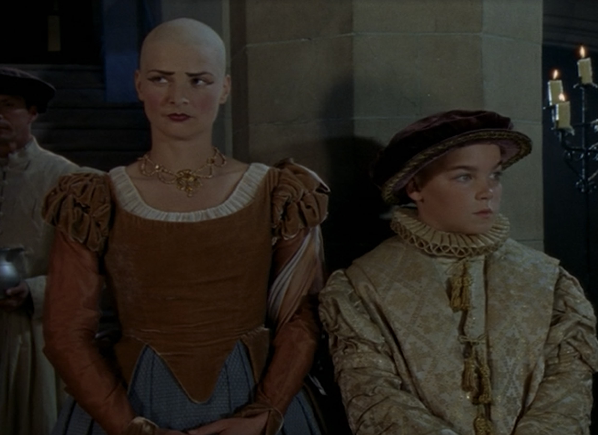 Susan Sheridan as Jane the Bald / Jane Foole wearing a brown and blue gown in the 2000 film "The Royal Diaries: Elizabeth I - Red Rose of the House of Tudor."
