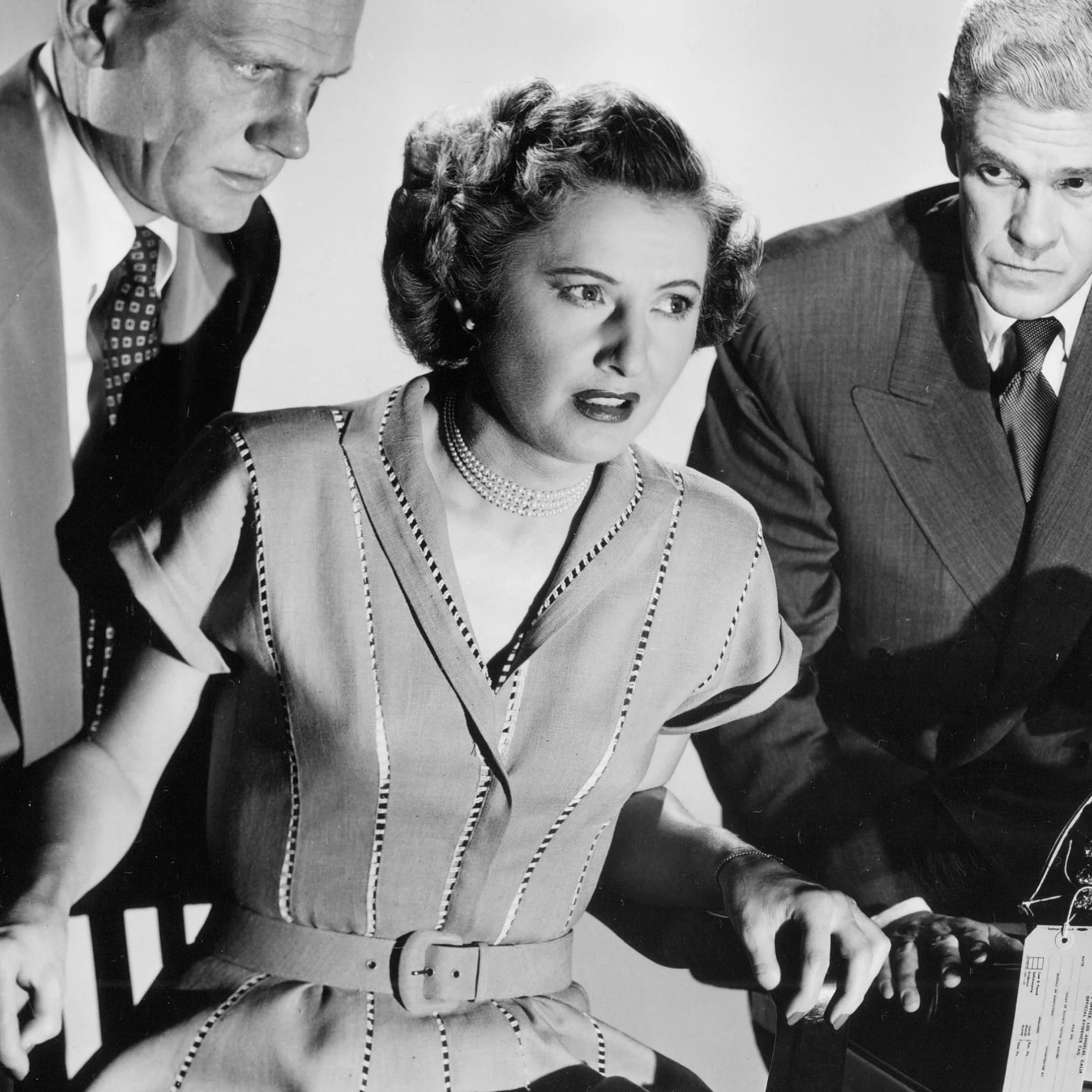 Barbara Stanwyck as Thelma Jordan wearing a dress decorated with open vertical stitching in the 1949 film "The File on Thelma Jordan."