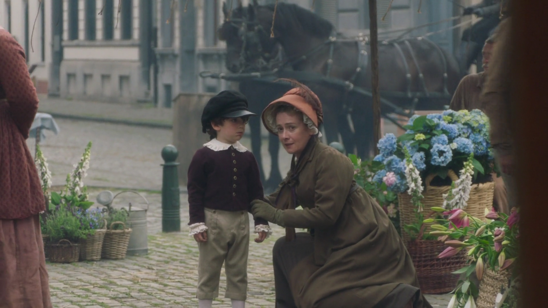 Raphael J. Bishop as young Marius Pontmercy wearing a brown-purple coat with a white collar in the 2018 miniseries "Les Misérables."