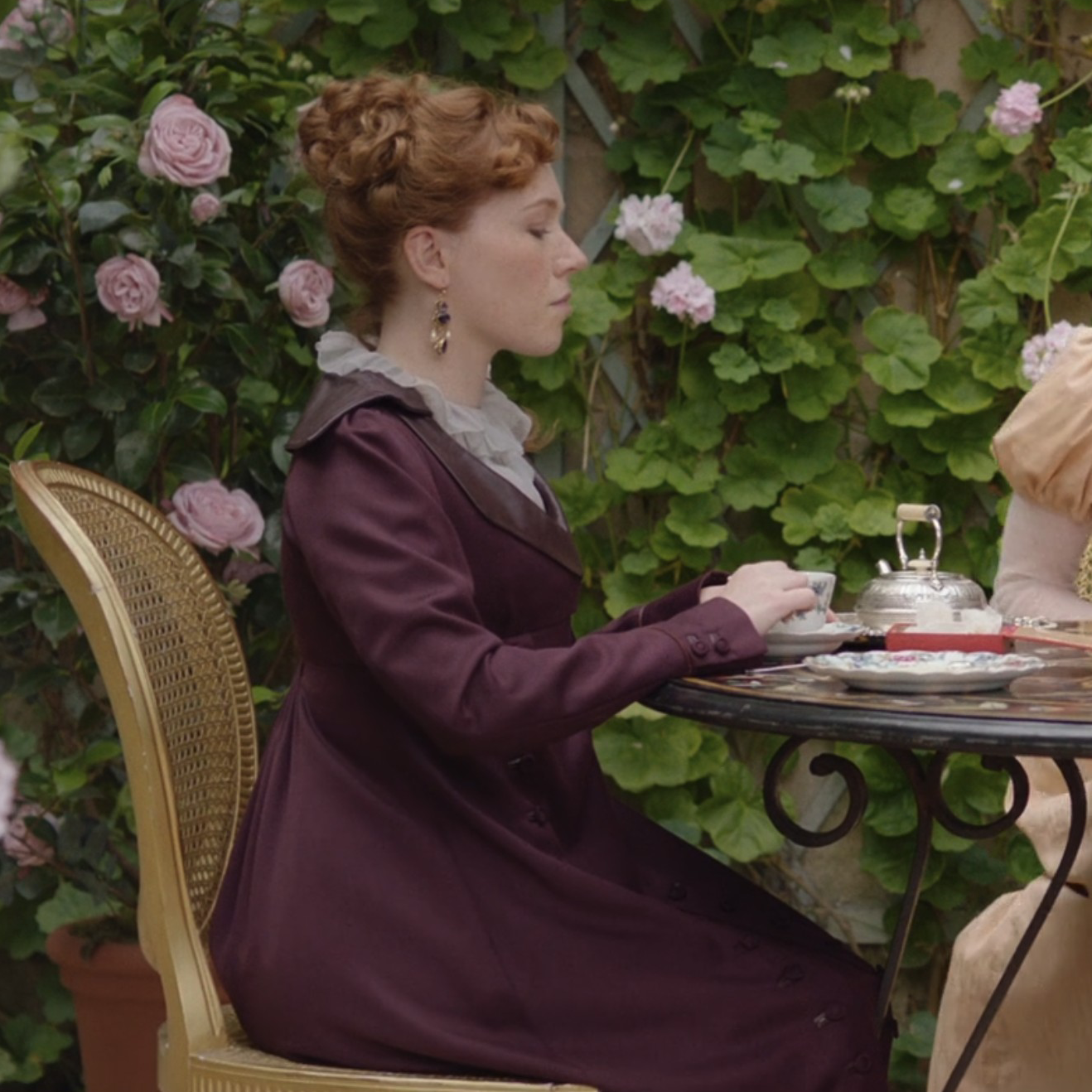 Charlotte Spencer as Esther Denham wearing a purple coat with a leather collar in the 2022 series "Sanditon."