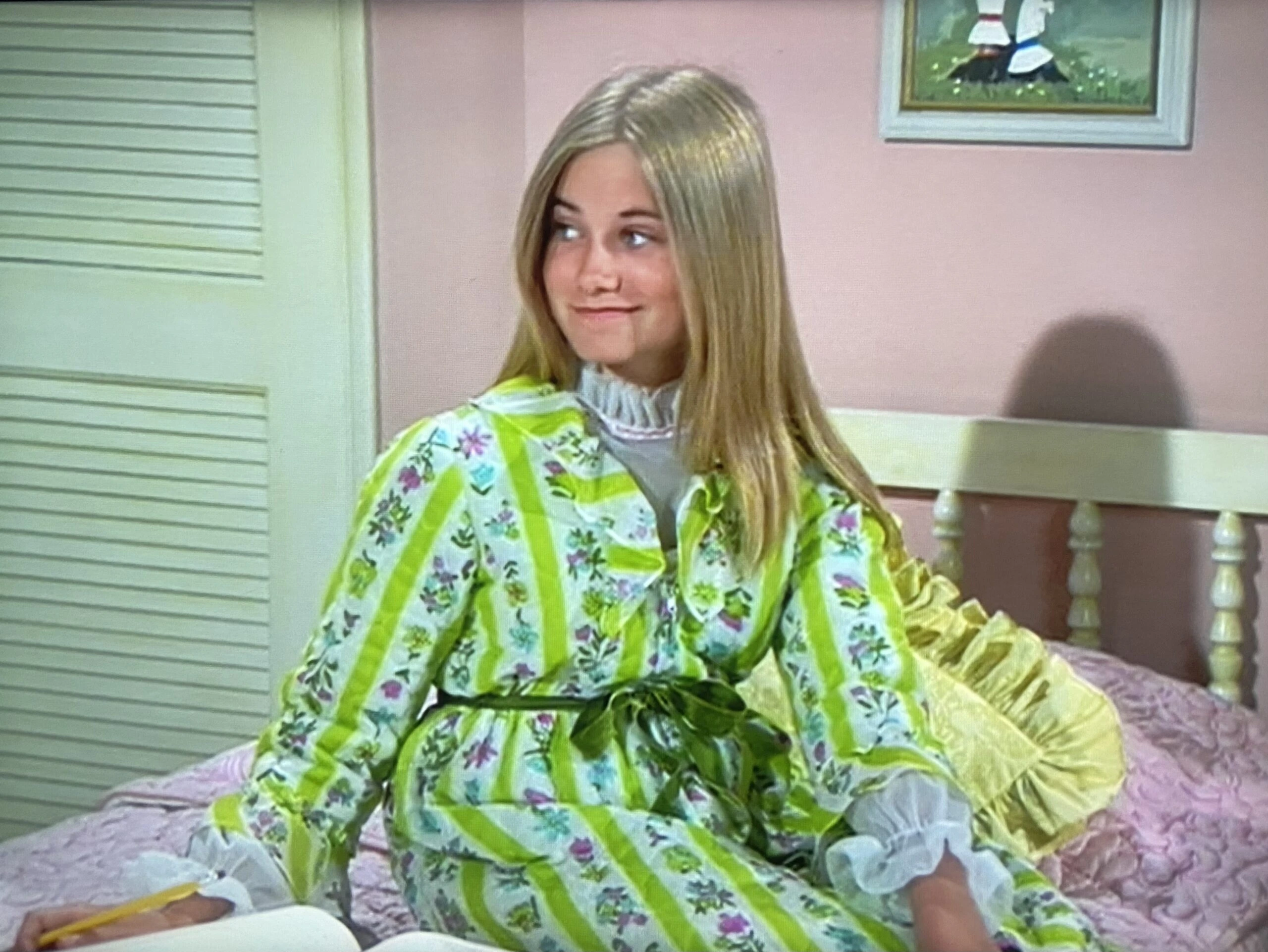 Maureen McCormick as Marcia Brady wearing a green and white striped bathrobe decorated with pink and blue flowers and belted with green velvet in the episode "The Hair-Brained Scheme" of the 1974 series "The Brady Bunch."