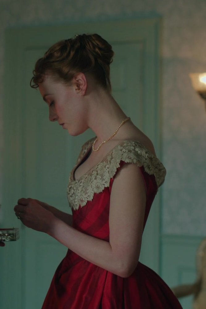 Harriet Slater as Clara Trenchard wearing a striped red gown decorated with lace in the 2024 series "Belgravia- The Next Chapter."