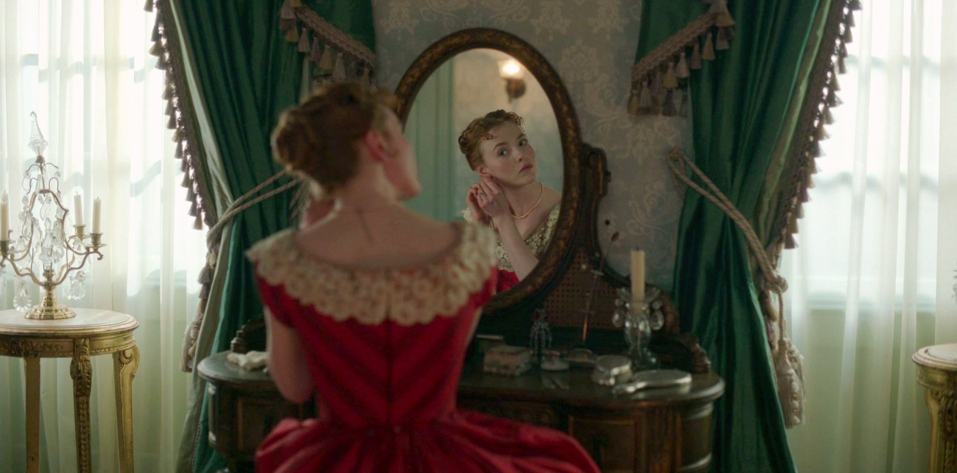 Harriet Slater as Clara Trenchard wearing a striped red gown decorated with lace in the 2024 series "Belgravia- The Next Chapter."