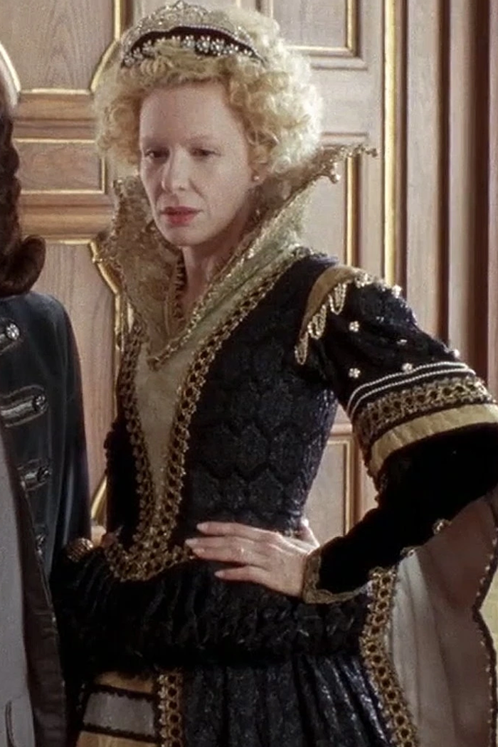Sunnyi Melles as Königsmutter (The King's Mother) wearing a black and gold gown in the 2009 film "Sechs auf einen Streich: Die kluge Bauerntochter" (Finest Fairy Tales: The Peasant's Wise Daughter).