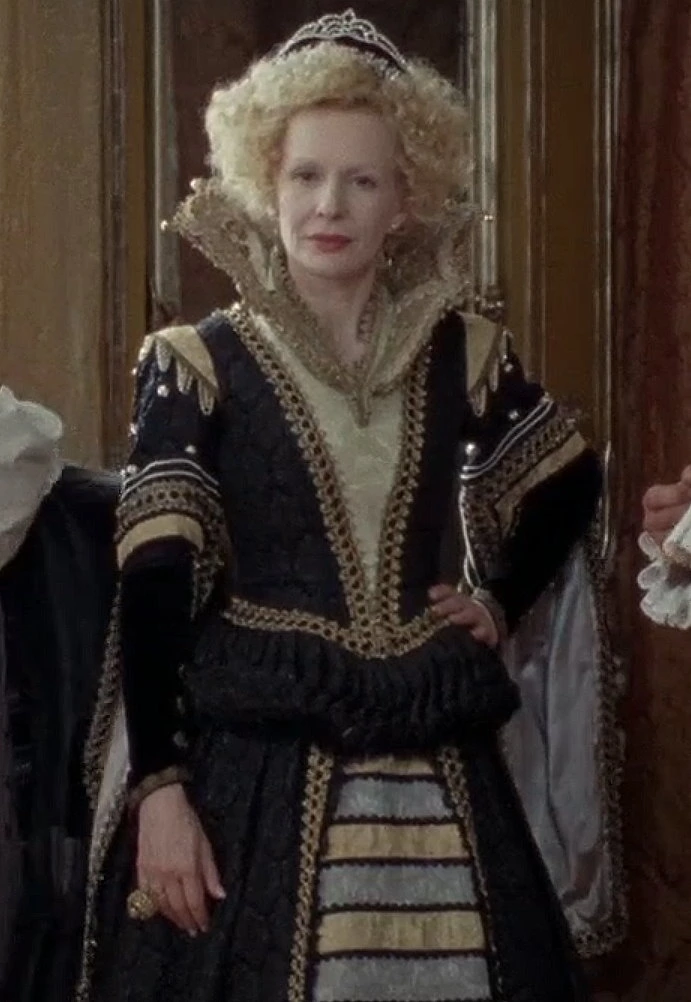 Sunnyi Melles as Königsmutter (The King's Mother) wearing a black and gold gown in the 2009 film "Sechs auf einen Streich: Die kluge Bauerntochter" (Finest Fairy Tales: The Peasant's Wise Daughter).