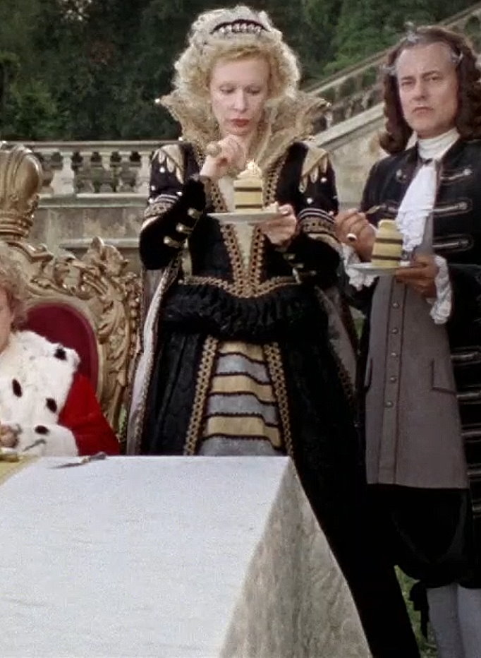 Sunnyi Melles as Königsmutter (The King's Mother) wearing a black and gold gown in the 2009 film "Sechs auf einen Streich: Die kluge Bauerntochter" (Finest Fairy Tales: The Peasant's Wise Daughter).