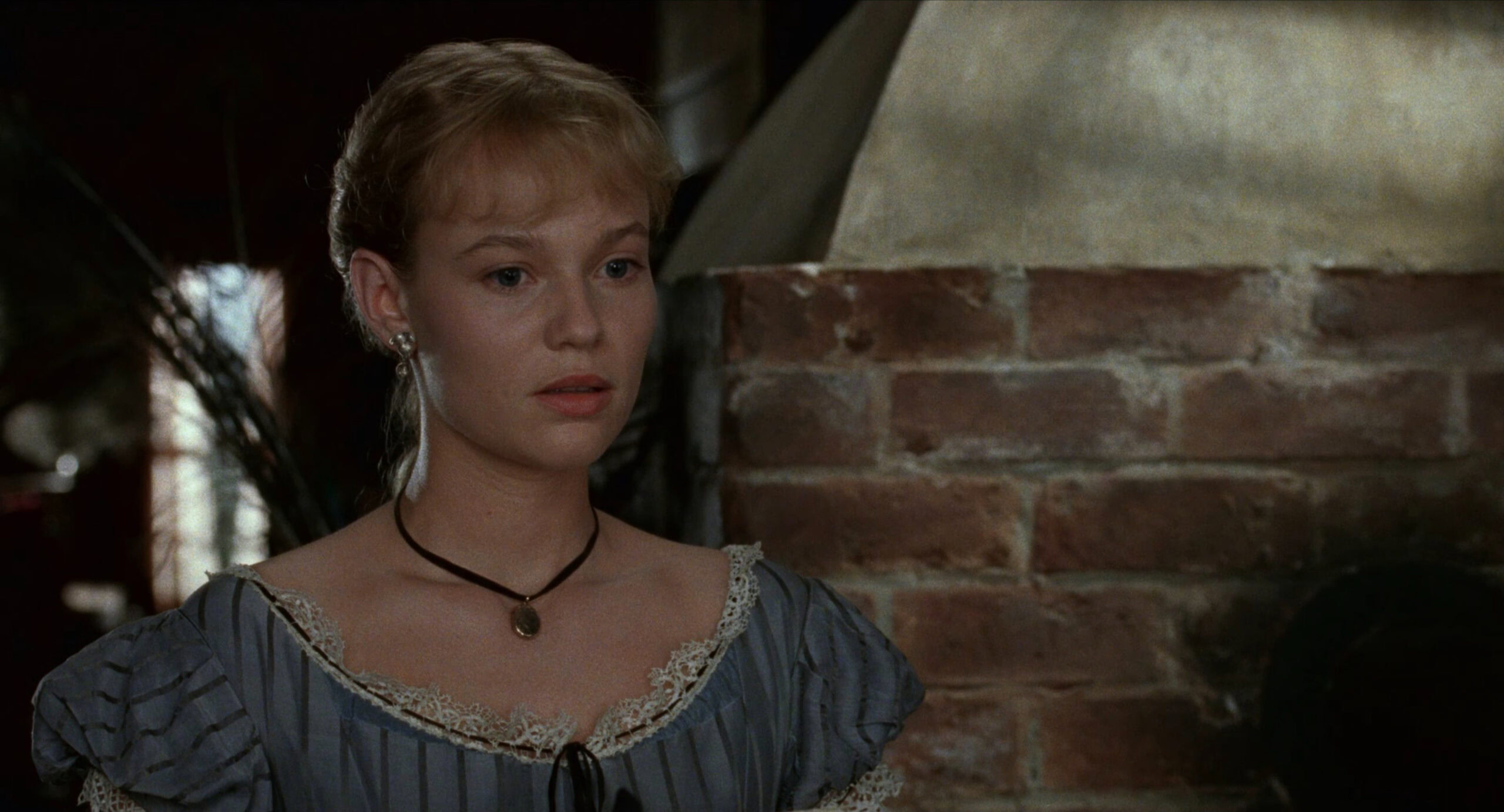 Samantha Mathis as Amy March wearing a blue striped dress decorated with lace and ribbon in the 1994 film "Little Women."