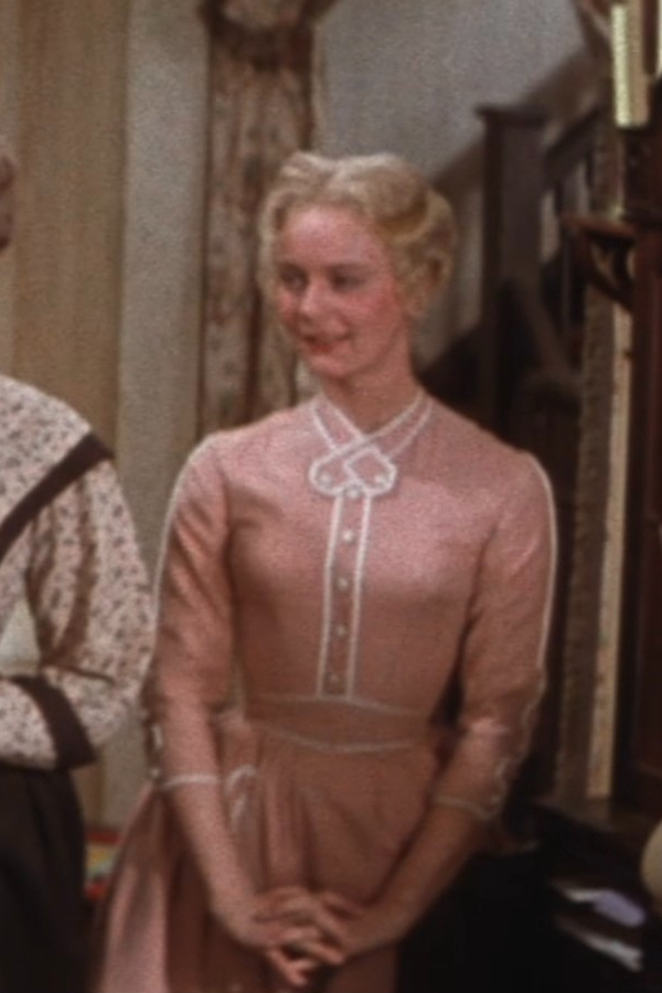 Nancy Kilgas as Alice wearing a pink dress with white detailing in the 1954 film "Seven Brides for Seven Brothers."